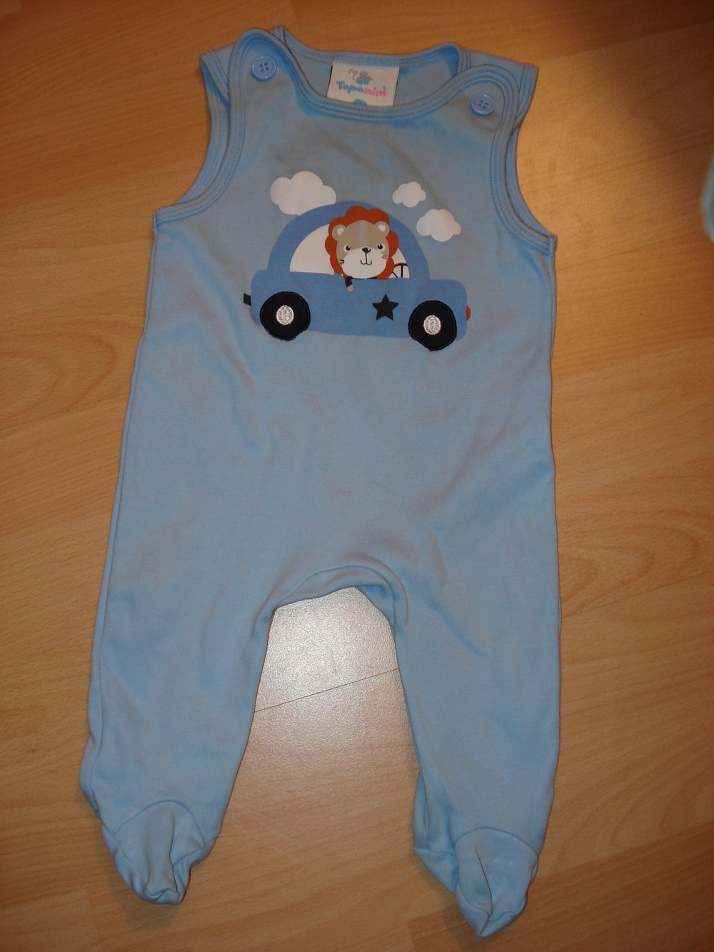 blauer Strampler mit autofahrendem Löwen