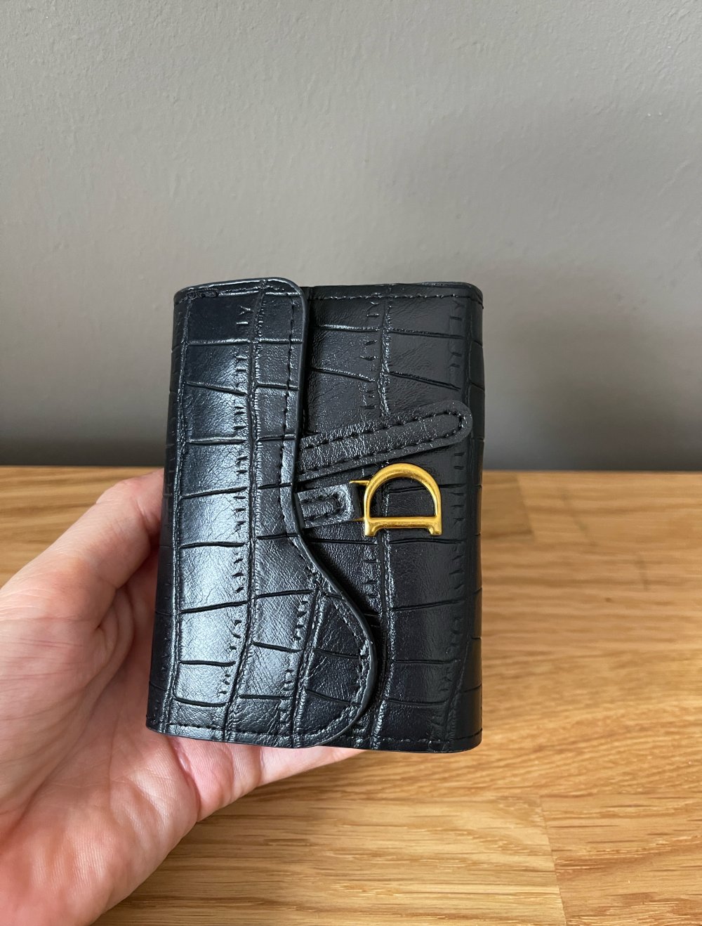 Schöner schwarzer Geldbeutel mit goldenem D in Krokooptik