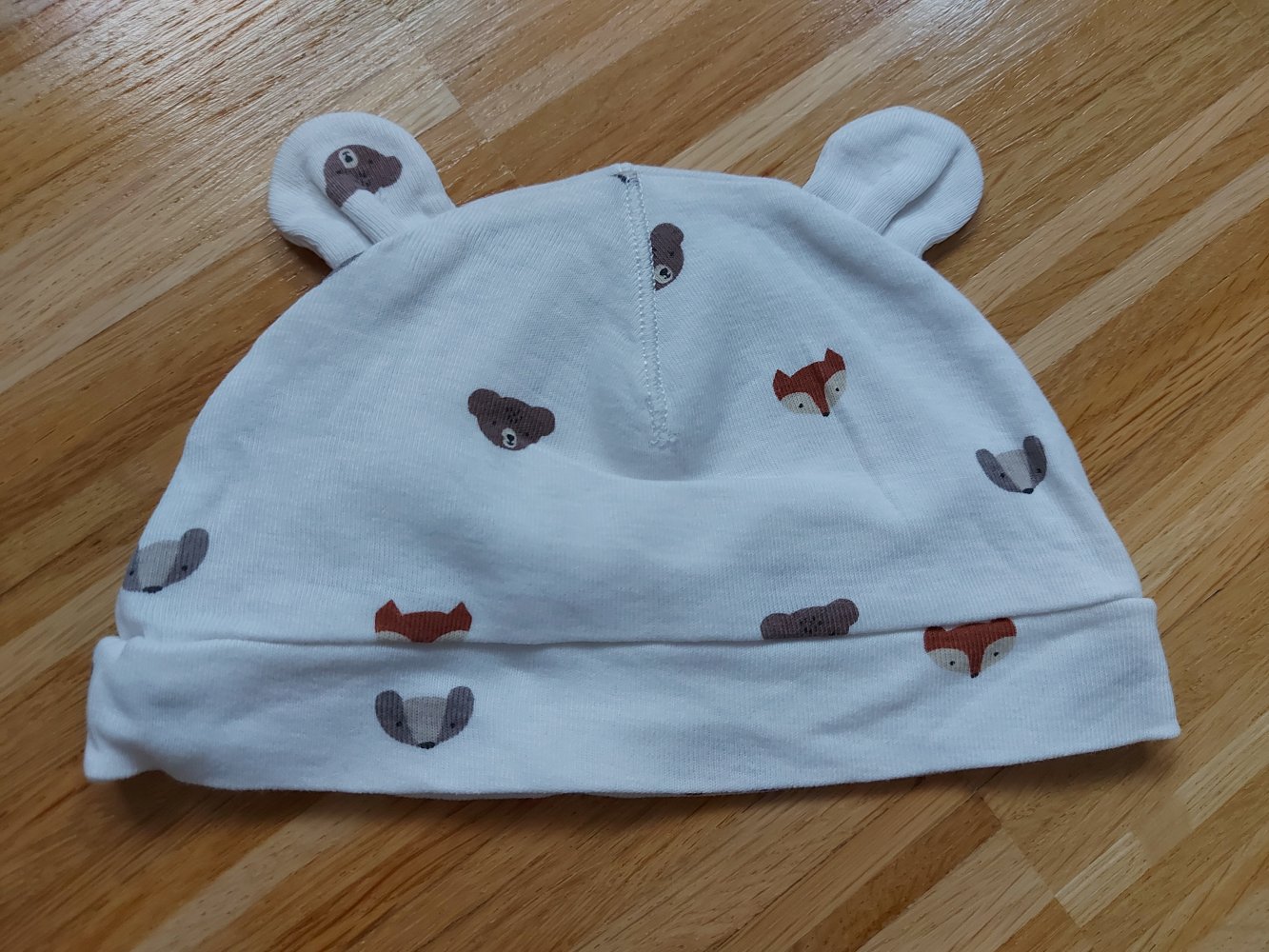 weiße Babymütze mit Öhrchen und Bär- und Fuchsmotiven