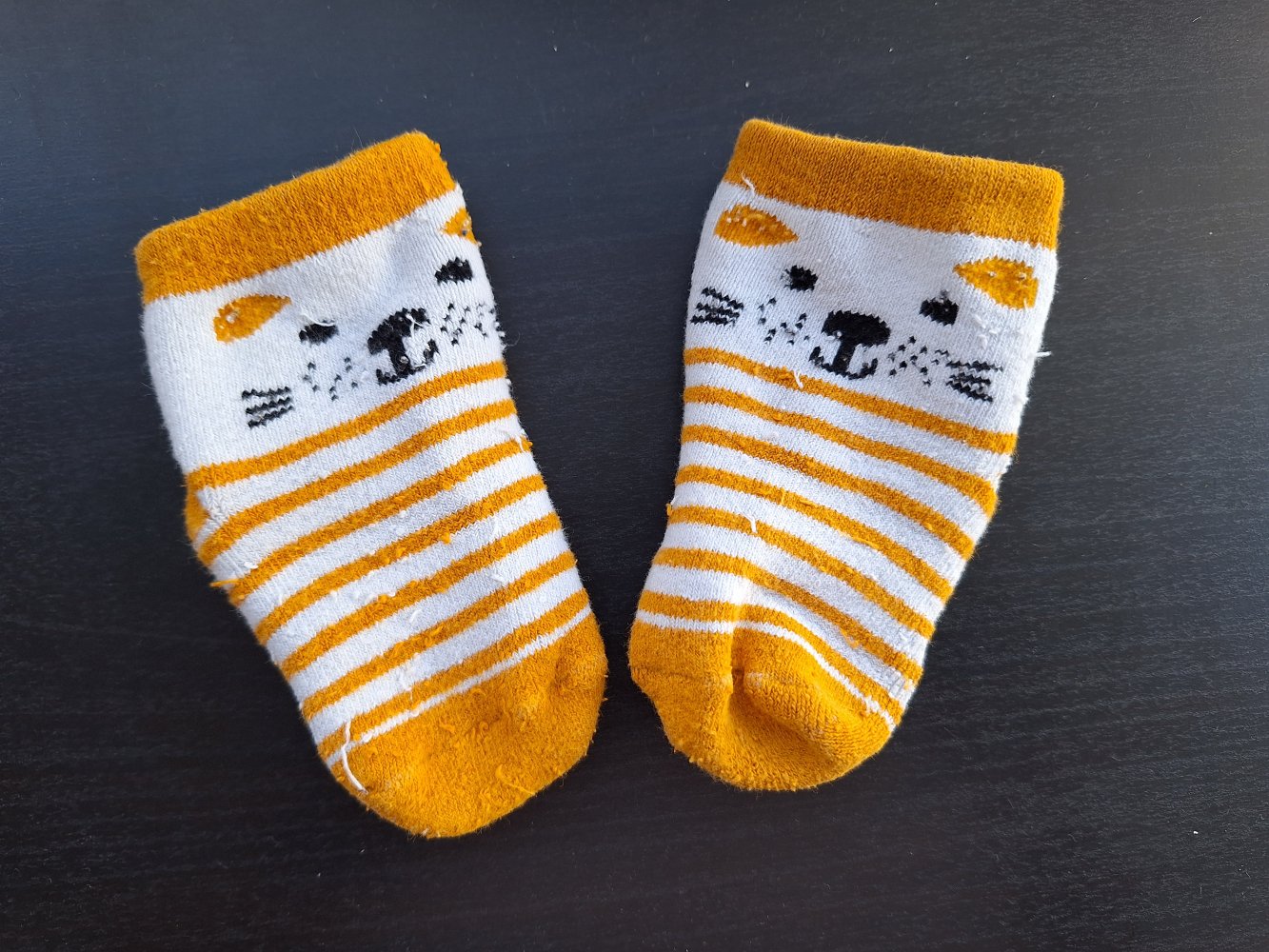 Weiß-orange Babysocken mit Stoppernoppen in Pfotenform